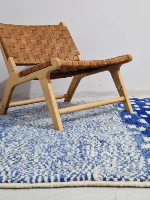 Handwoven wool rug with a checked abstract pattern on a blue background in wall decorated room