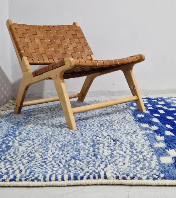 Handwoven wool rug with a checked abstract pattern on a blue background in wall decorated room