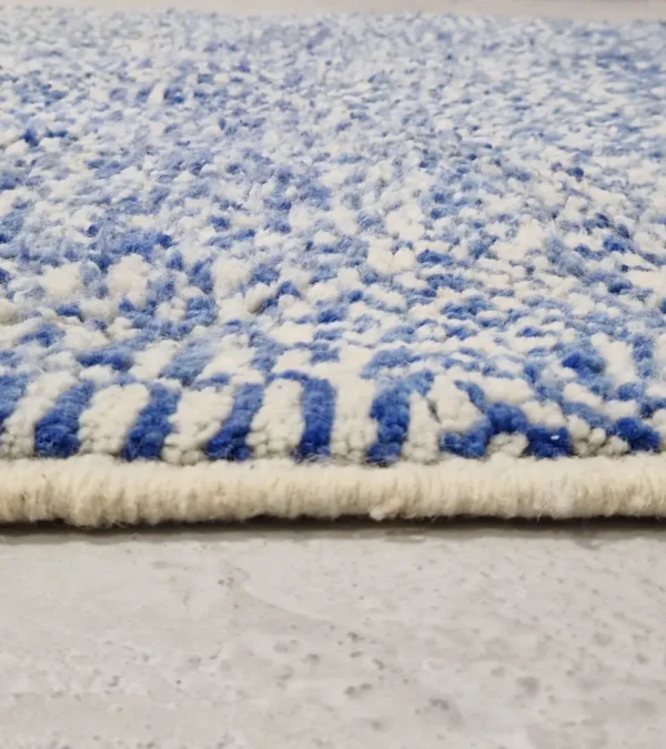 Zoomed In View of Handwoven wool rug with a checked abstract pattern on a blue background
