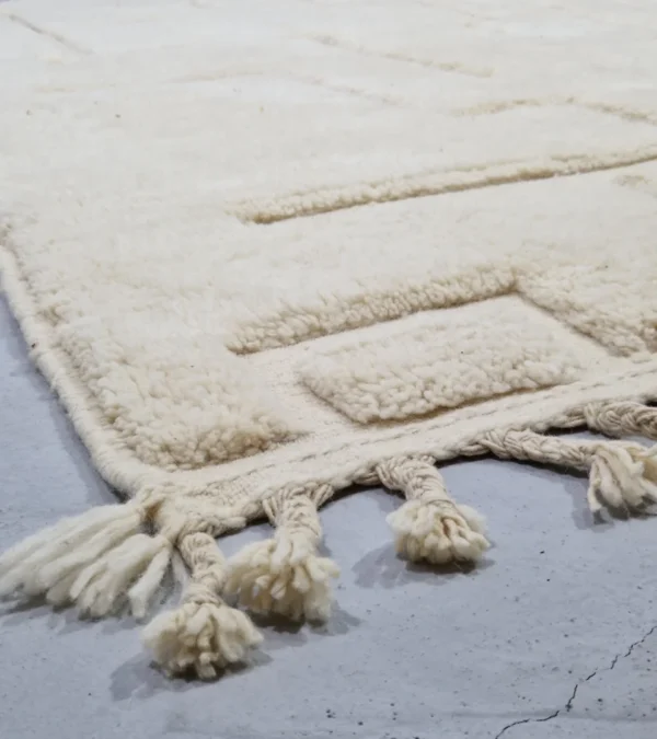 Detailed View of Moroccan hand-knotted ivory wool rug with raised geometric pattern and tassels