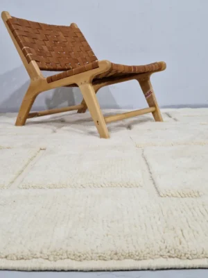 Moroccan hand-knotted ivory wool rug with raised geometric pattern and tassels in lifestyle sitting