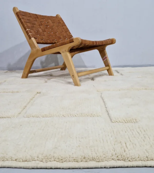Moroccan hand-knotted ivory wool rug with raised geometric pattern and tassels in lifestyle sitting