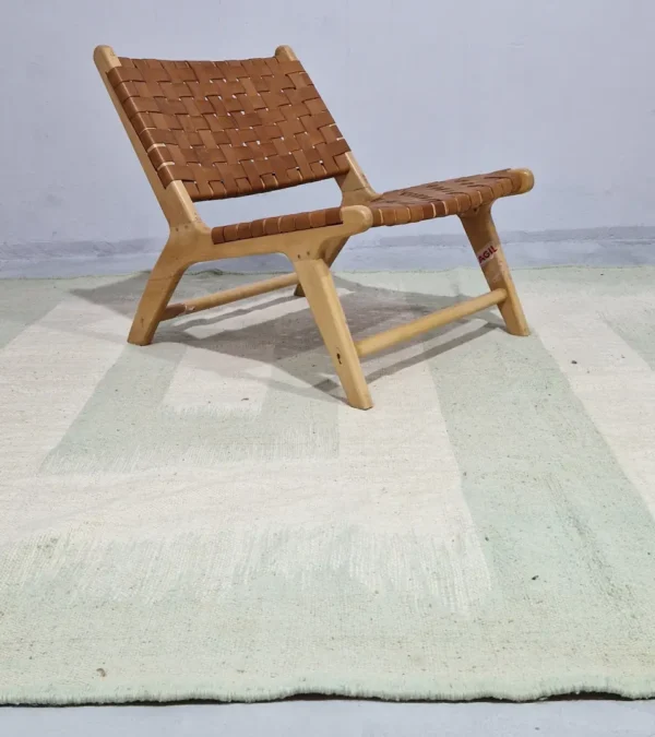 Adel handmade Kilim flatweave wool rug with a pale green background and a white geometric pattern in room