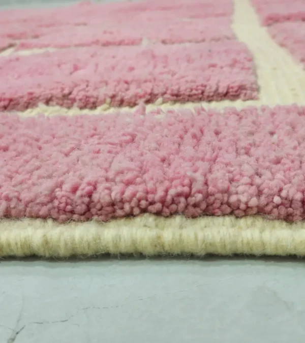 Zoomed In View of Aivra handmade Beni Ourain wool rug with a minimalist pink and ivory labyrinth design