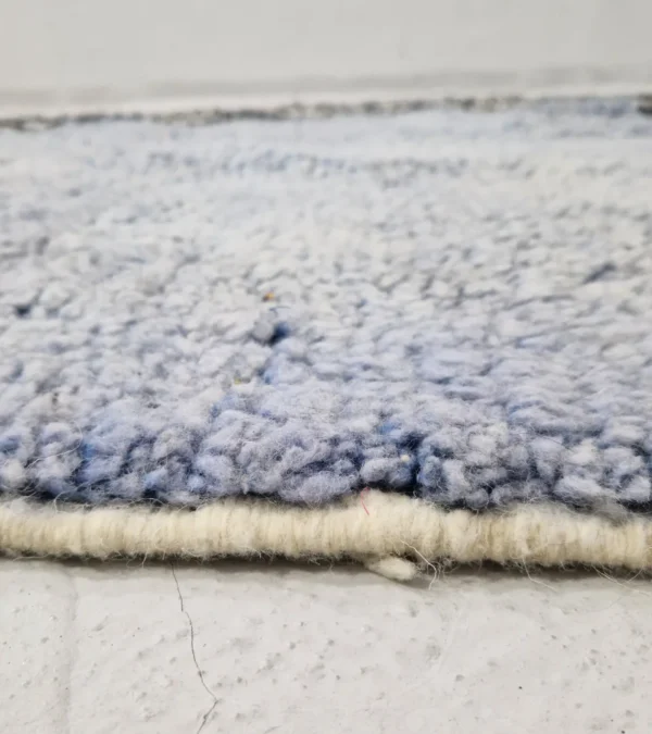 Zoomed In View of Handmade Moroccan wool rug with a minimalist block and stripe design in blue, black, and white