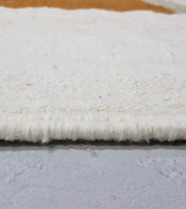 Zoomed In View of Aline handmade Kilim flatweave rug with a sawtooth pattern in brown, light green, and ivory