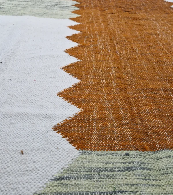 Detailed View of Aline handmade Kilim flatweave rug with a sawtooth pattern in brown, light green, and ivory