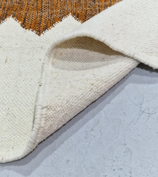 Detailed View of Aline handmade Kilim flatweave rug with a sawtooth pattern in brown, light green, and ivory