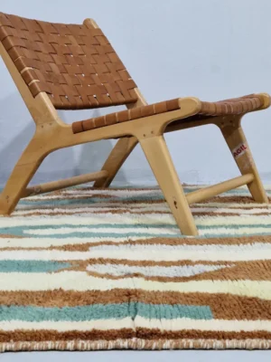 Handmade Moroccan wool rug with an abstract brushstroke design in cream, beige, blue, and yellow on a brown background in room