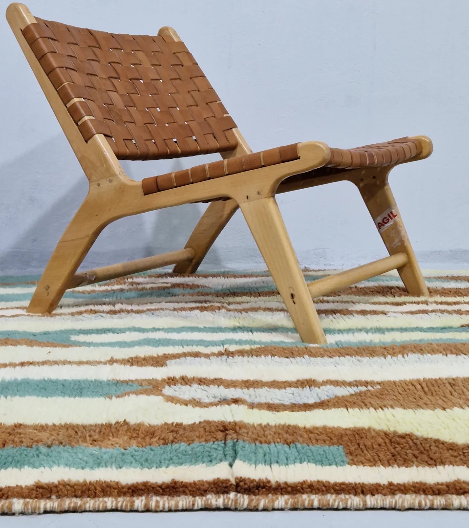 Handmade Moroccan wool rug with an abstract brushstroke design in cream, beige, blue, and yellow on a brown background in room