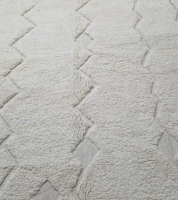 Detailed View of Berry handmade Beni Mrirt wool rug with a subtle raised geometric pattern on an ivory background