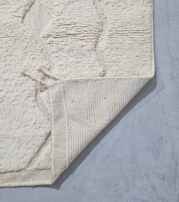 Detailed View of Berry handmade Beni Mrirt wool rug with a subtle raised geometric pattern on an ivory background