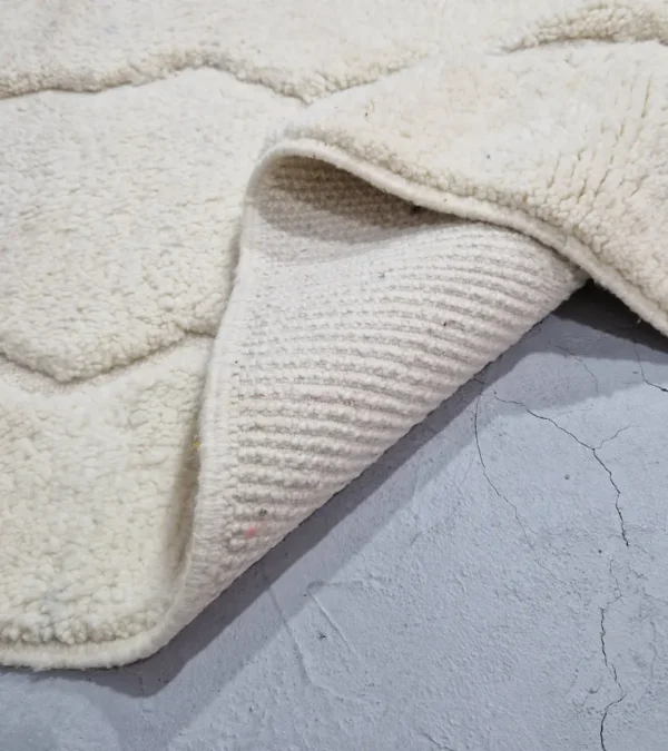 Detailed View of Berry handmade Beni Mrirt wool rug with a subtle raised geometric pattern on an ivory background