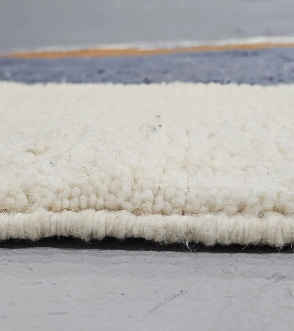 Zoomed In View of Handmade Beni Ourain wool rug with a contemporary abstract design in blue, brown, pink, and yellow