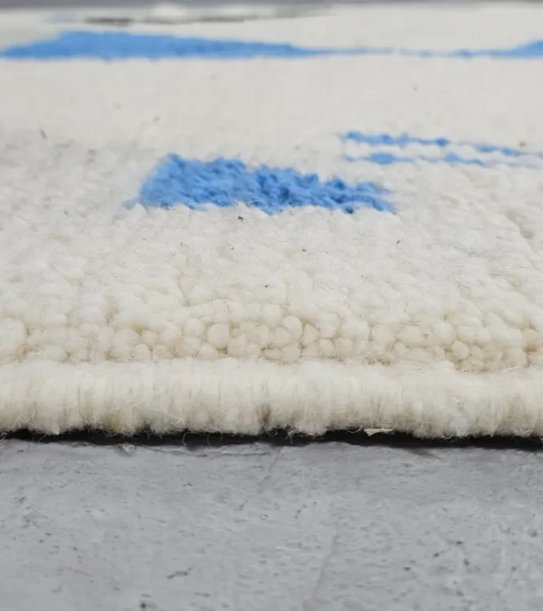 Zoomed In View of Diana handmade Beni Ourain wool rug with a contemporary abstract design in blues, grays, black, and green