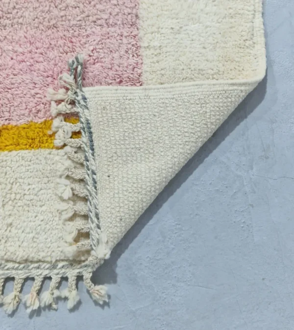 Detailed View of Elly handmade wool rug with a minimalist pastel colorblocked design in pink, yellow, and gray