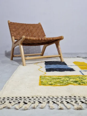 Emy handmade Beni Ourain wool rug with a modern abstract design featuring green, yellow, navy blue, light blue, and white color blocks outlined in yellow in room