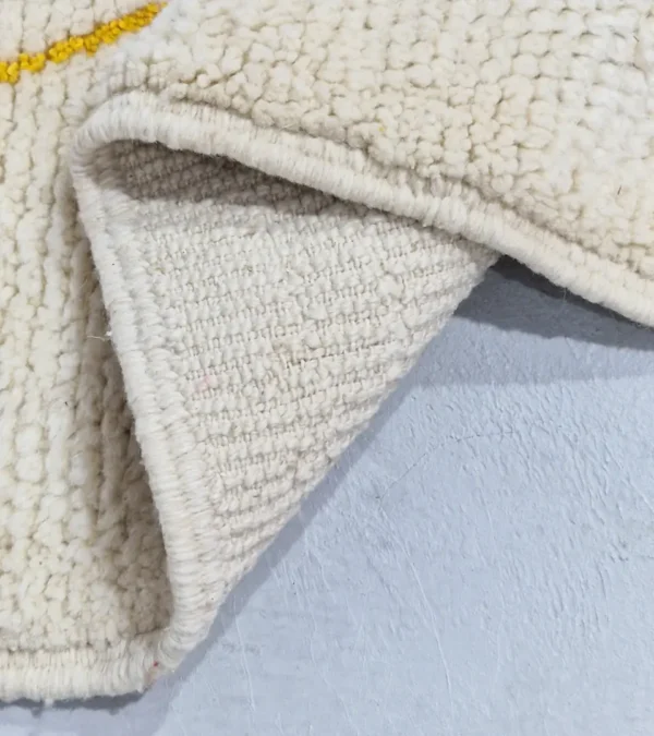 Detailed View of Emy handmade Beni Ourain wool rug with a modern abstract design featuring green, yellow, navy blue, light blue, and white color blocks outlined in yellow