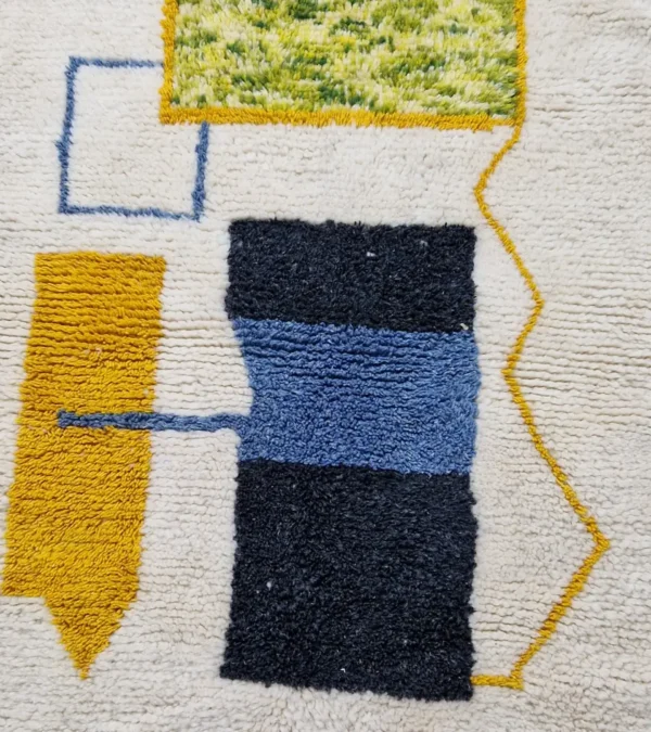 Detailed View of Emy handmade Beni Ourain wool rug with a modern abstract design featuring green, yellow, navy blue, light blue, and white color blocks outlined in yellow