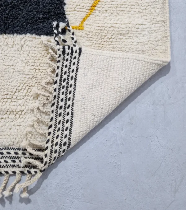Detailed View of Emy handmade Beni Ourain wool rug with a modern abstract design featuring green, yellow, navy blue, light blue, and white color blocks outlined in yellow