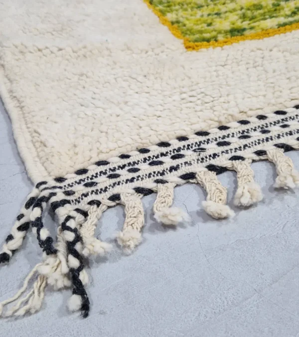 Detailed View of Emy handmade Beni Ourain wool rug with a modern abstract design featuring green, yellow, navy blue, light blue, and white color blocks outlined in yellow