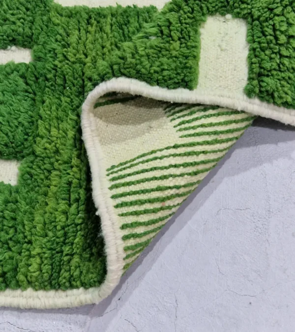 Detailed View of Frez handmade wool rug with a minimalist green line pattern and ivory background