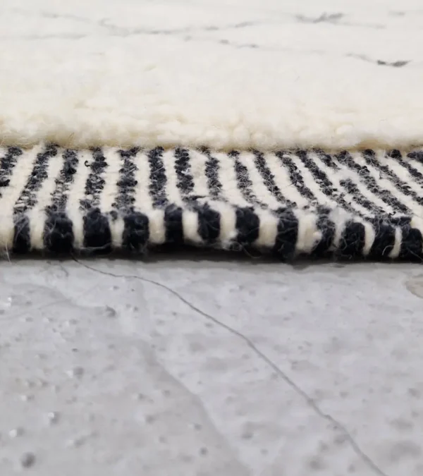 Zoomed In View of Ghita handmade Beni Ourain wool rug with a classic dark diamond pattern on an ivory background