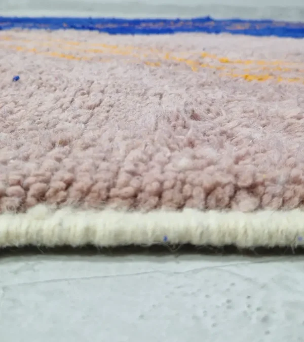 Zoomed In View of Handwoven Moroccan rug with a jagged blue and beige design and yellow zigzag lines