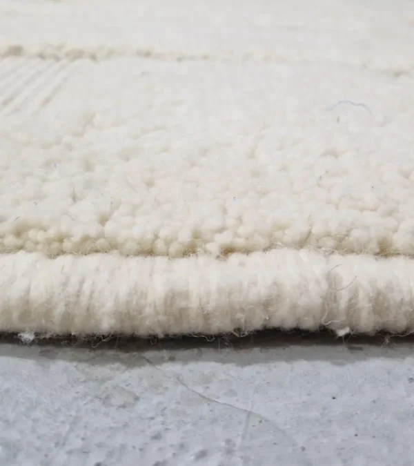 Zoomed In View of handmade Moroccan wool rug with a subtle geometric design created by varying pile heights in neutral tones