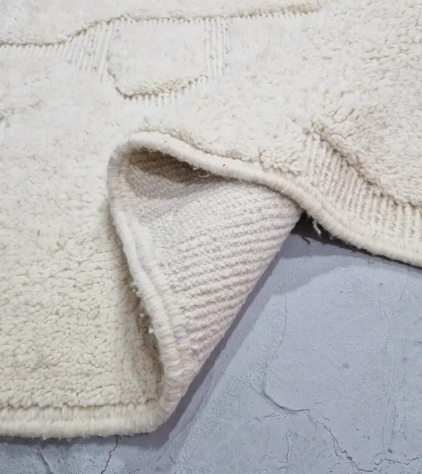 Detailed View of handmade Moroccan wool rug with a subtle geometric design created by varying pile heights in neutral tones