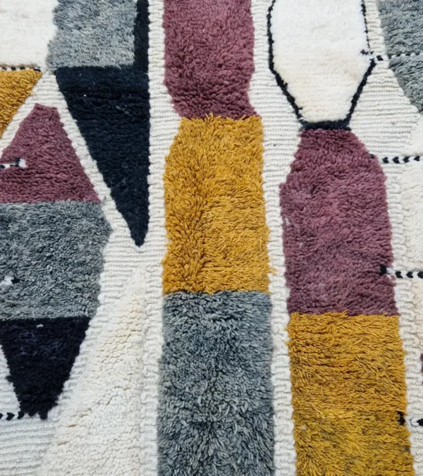 Detailed View of Imani handmade Beni Ourain wool rug with a boho geometric high-low design in multicolor hues including plum, yellow, black, and gray