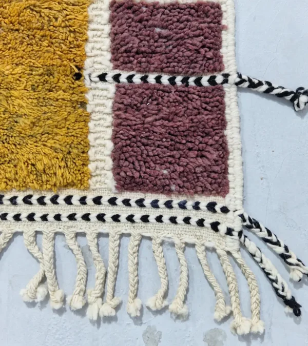 Detailed View of Imani handmade Beni Ourain wool rug with a boho geometric high-low design in multicolor hues including plum, yellow, black, and gray