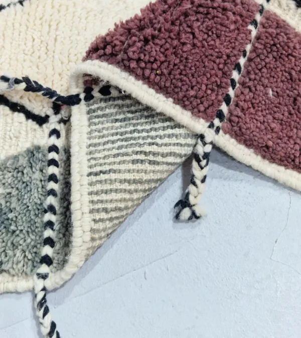 Detailed View of Imani handmade Beni Ourain wool rug with a boho geometric high-low design in multicolor hues including plum, yellow, black, and gray