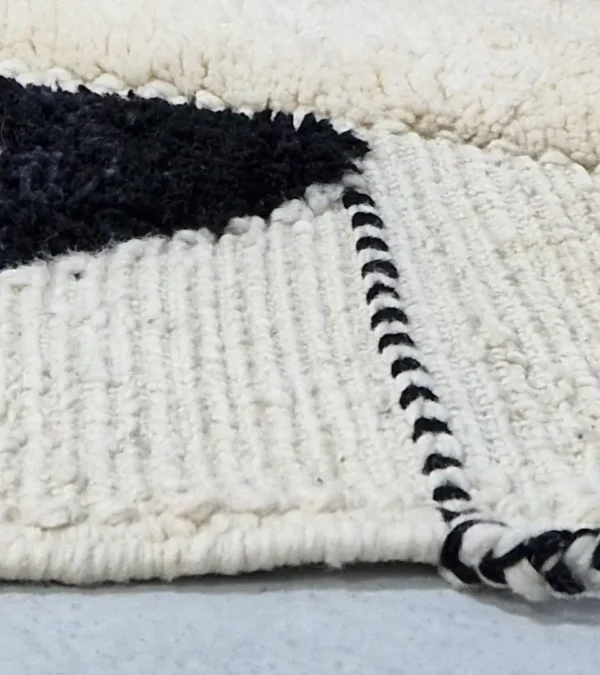 Zoomed In View of Imani handmade Beni Ourain wool rug with a boho geometric high-low design in multicolor hues including plum, yellow, black, and gray