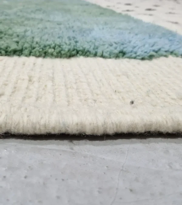 Zoomed In View of Johana handmade Moroccan wool rug with a modern dotted pattern and two-tone green and ivory design