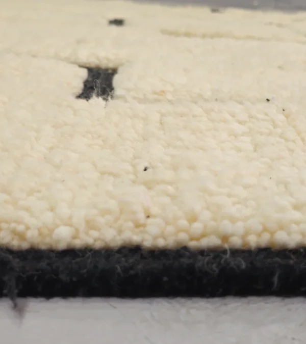 Zoomed In View of Handmade Moroccan Beni Ourain wool rug with abstract striped pattern in ivory and black