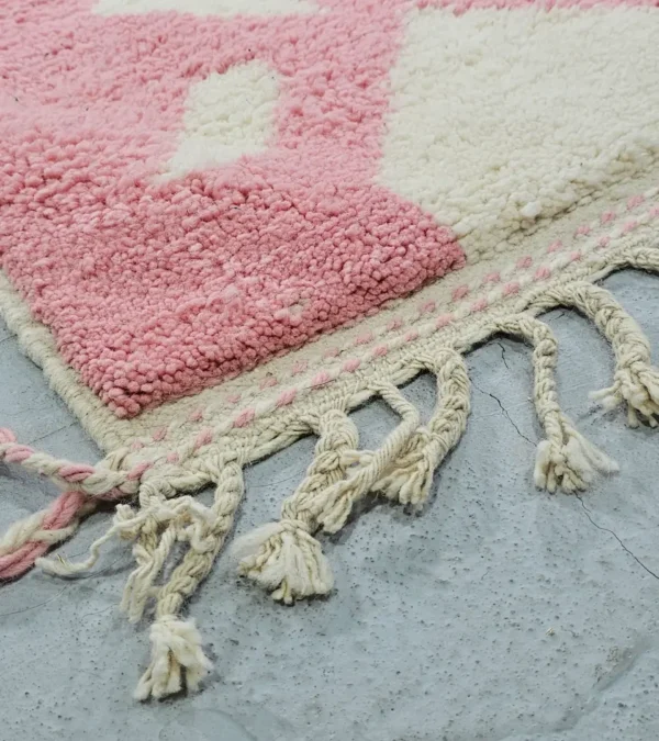 Detailed View of Juju handmade Moroccan wool rug with a contemporary geometric pattern in pink and ivory