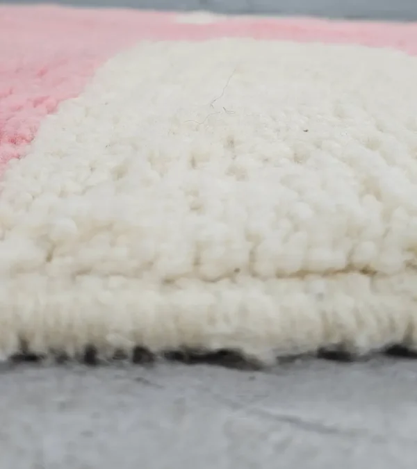 Zoomed In View of Juju handmade Moroccan wool rug with a contemporary geometric pattern in pink and ivory
