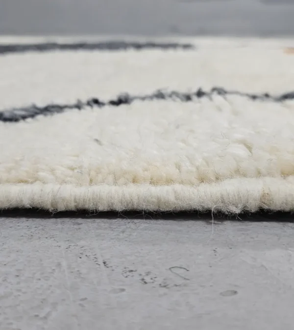 Zoomed In View of Kita handmade Beni Ourain wool rug with a minimalist abstract design in brown, black, and ivory