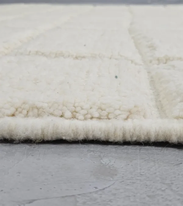 Zoomed In View of Lara handmade Beni Mrirt wool rug with a minimalist grid pattern in ivory created with a high/low pile