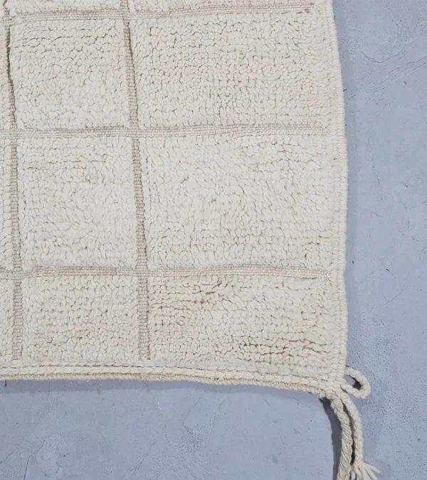 Detailed View of Lara handmade Beni Mrirt wool rug with a minimalist grid pattern in ivory created with a high/low pile