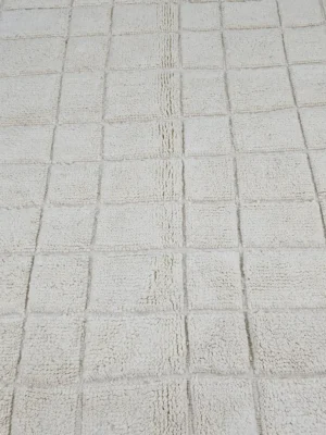 Detailed View of Lara handmade Beni Mrirt wool rug with a minimalist grid pattern in ivory created with a high/low pile