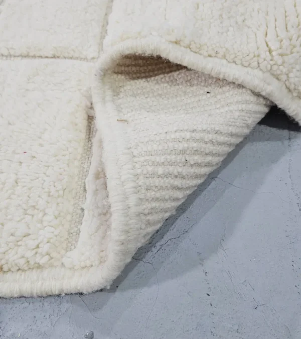Detailed View of Lara handmade Beni Mrirt wool rug with a minimalist grid pattern in ivory created with a high/low pile