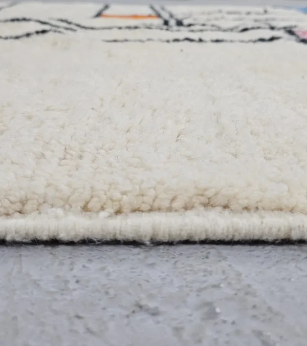 Zoomed In View of Lina handmade Beni Ourain wool rug with a geometric lined design in black, ivory, blue, pink, orange, and teal