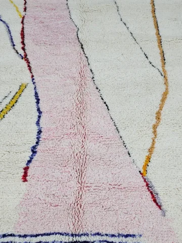 Detailed View of Handmade Moroccan Azilal wool rug with unique abstract pink, yellow, blue, and brown lines and shapes on an ivory background