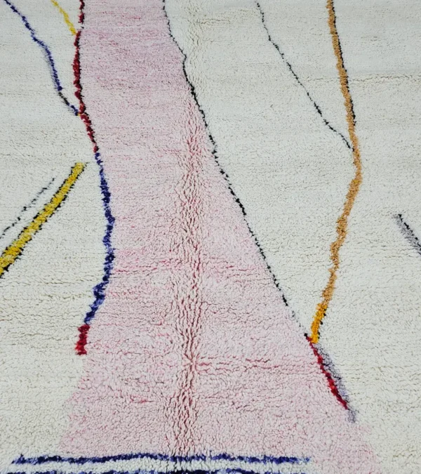 Detailed View of Handmade Moroccan Azilal wool rug with unique abstract pink, yellow, blue, and brown lines and shapes on an ivory background