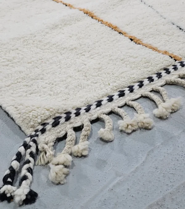 Detailed View of Handmade Moroccan Azilal wool rug with unique abstract pink, yellow, blue, and brown lines and shapes on an ivory background
