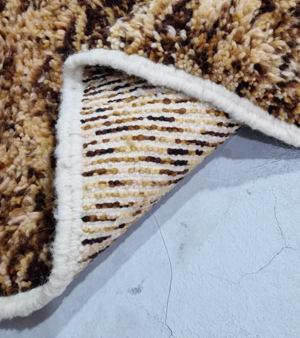 Detailed View of Luna handmade Beni Ourain wool rug with a boho brown background and a geometric pattern in ivory and blue