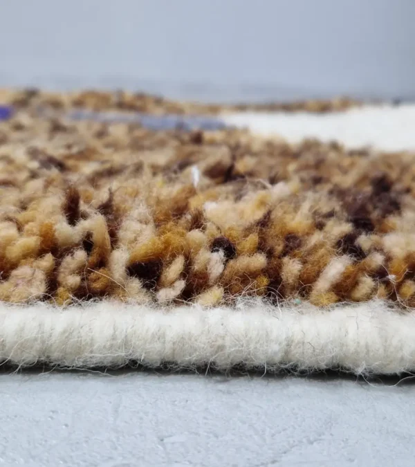 Zoomed In View of Luna handmade Beni Ourain wool rug with a boho brown background and a geometric pattern in ivory and blue