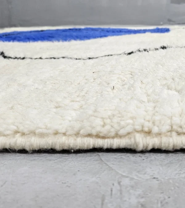 Zoomed In View of Handmade Moroccan wool rug with blue and mustard abstract design and black outline
